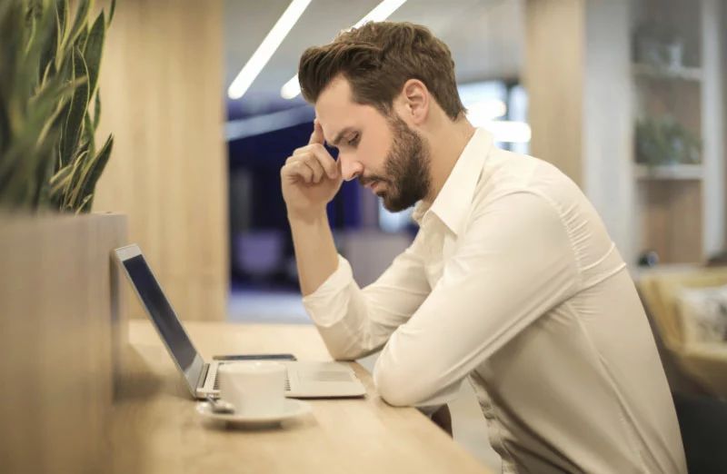 man looking at computer with a headache